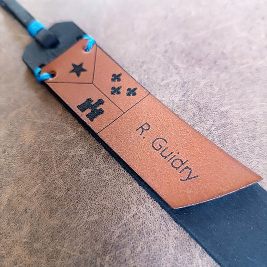 A personalized Cajun leather bookmark with an Acadian flag, close up view of engraving