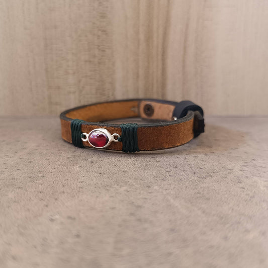 Close-up of the Minimal Red Garnet Leather Wrap Bracelet, highlighting the hand-cut natural red garnet set in sterling silver, decorated with deep forest green waxed cord.