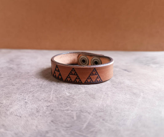 Brown leather bracelet with geometric pattern on a light gray surface