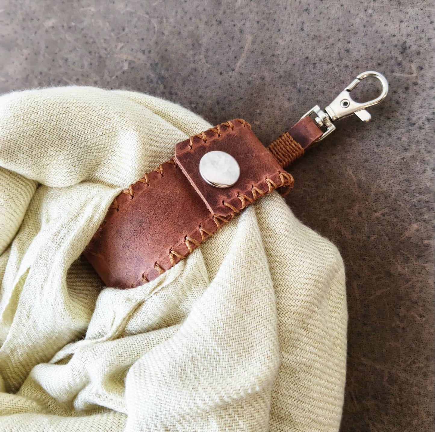 Handmade leather scarf holder with scarf attached and lobster clasp to clip on a bag