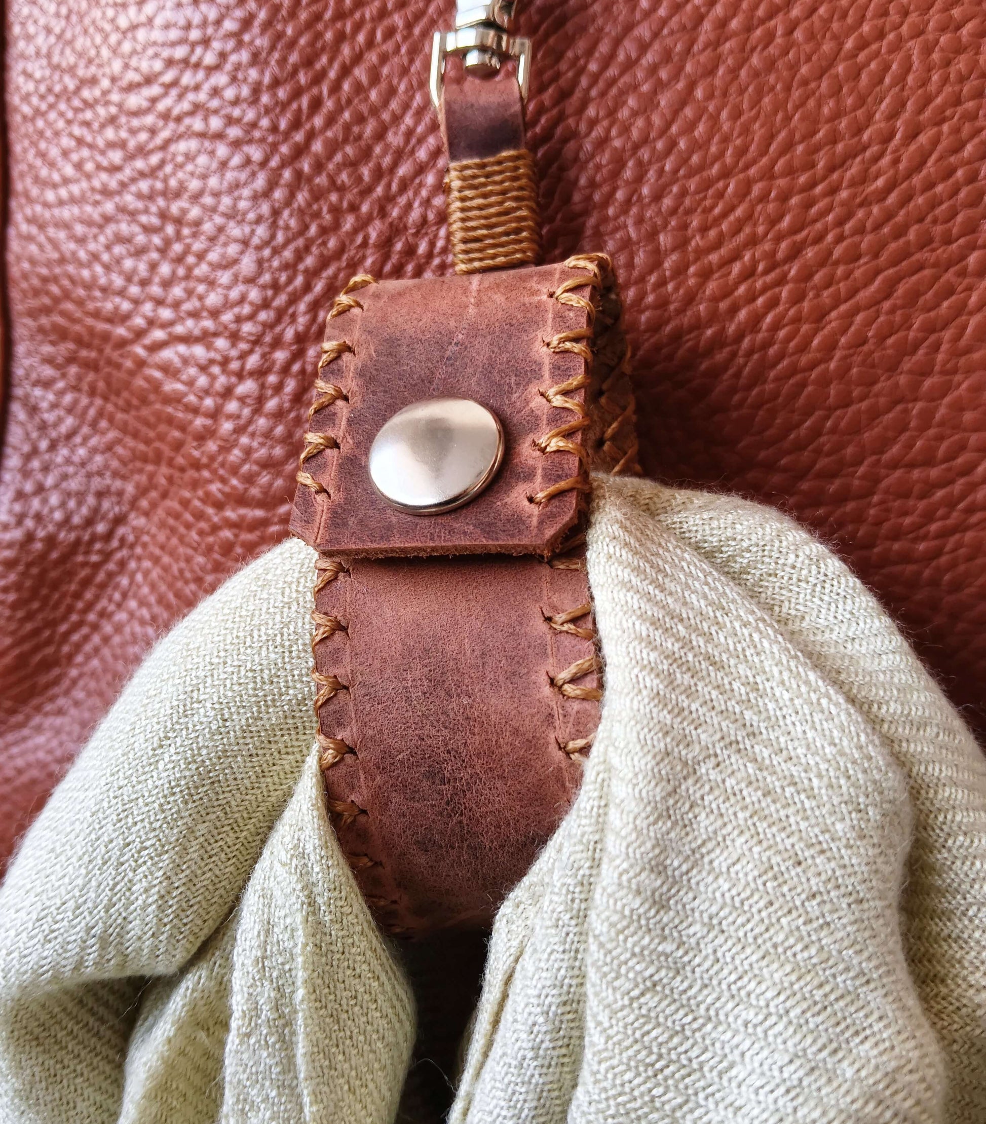 Dark brown leather scarf holder attached to a handbag