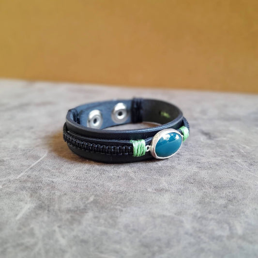 The OOAK Green Aventurine Black Leather Bracelet side view: A layered black Vachetta leather cuff with black macramé, featuring a prominent natural dark green Aventurine stone set in a sterling silver pendant.