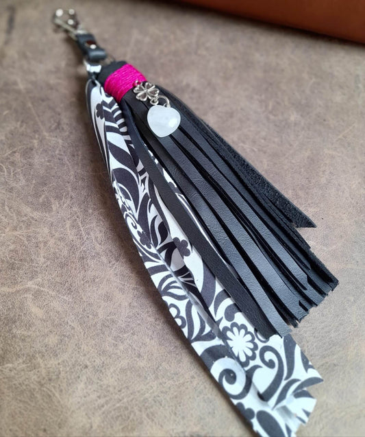 Detailed close-up of the natural Moonstone heart pendant and the stainless steel four-leaf clover charm on the black leather tassel, highlighting the stone's shimmer.