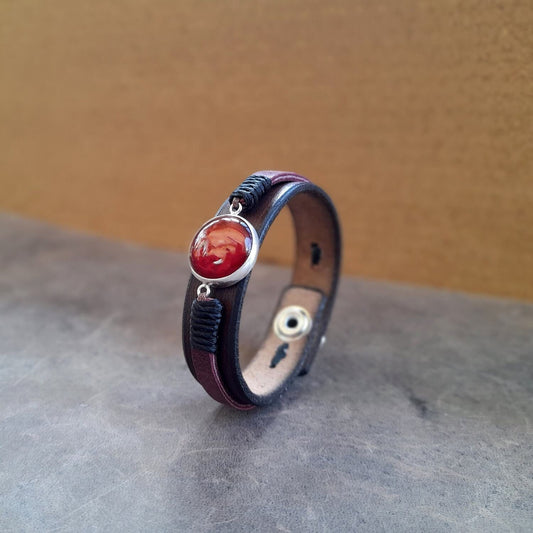 The OOAK Red Carnelian Leather Bracelet: A layered chestnut brown leather cuff featuring a prominent large natural red Carnelian stone set in a polished sterling silver 925 cabochon.
