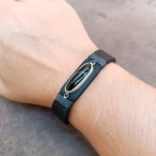 The Eclipse is a one-of-a-kind black obsidian leather bracelet with a handcrafted sterling silver pendant, premium black vachetta leather and unique natural vein.