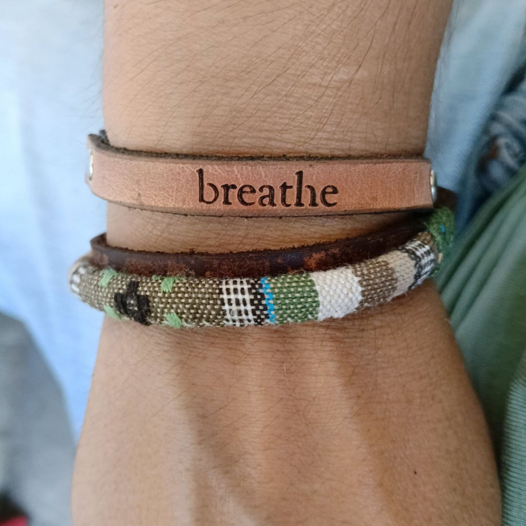 A handmade leather wrap bracelet with a distressed green and brown finish, worn on wrist.