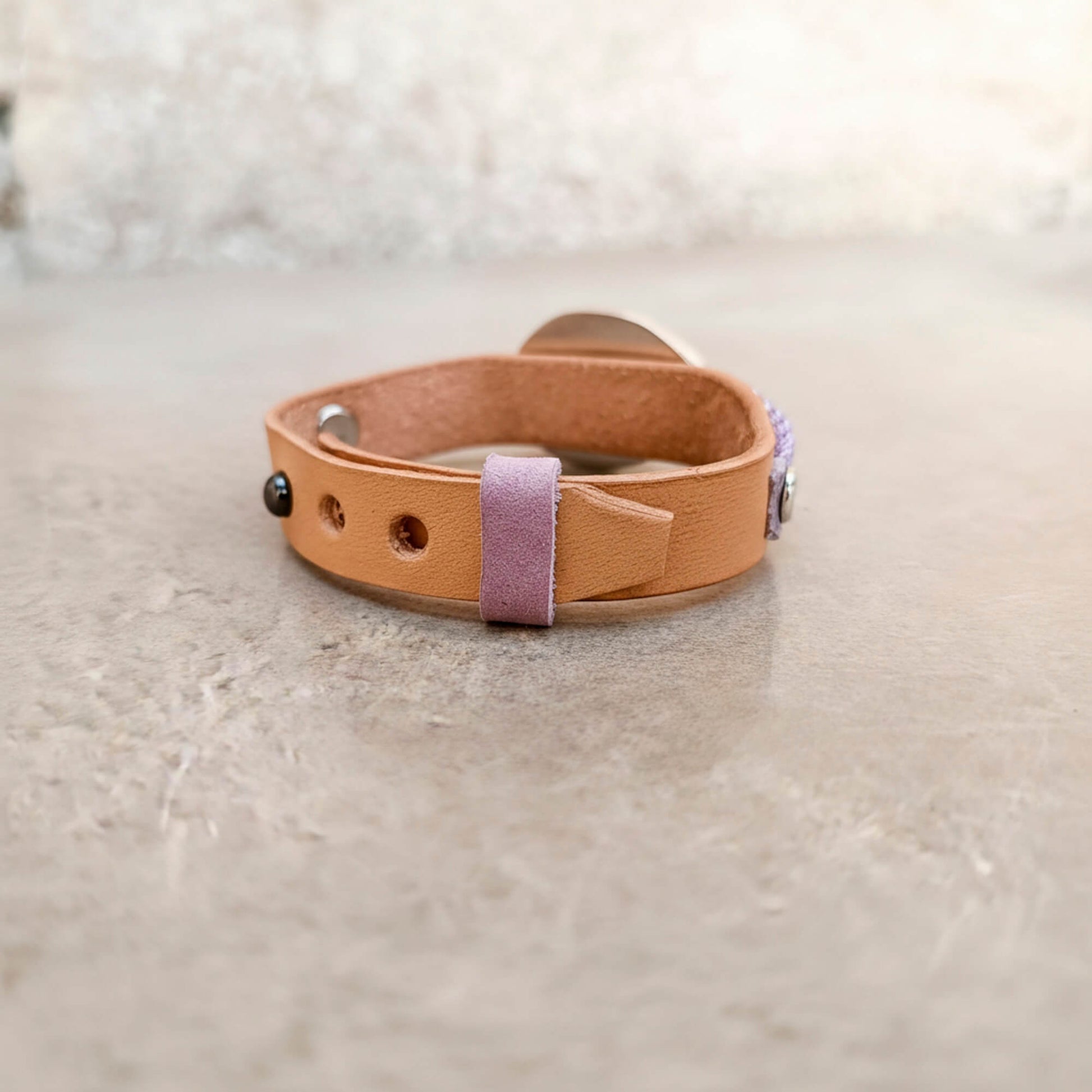 A one-of-a-kind handcrafted leather bracelet featuring a large raw druzy rose quartz set in a handcrafted sterling silver pendant on a slim watchband-style leather cuff, backside view