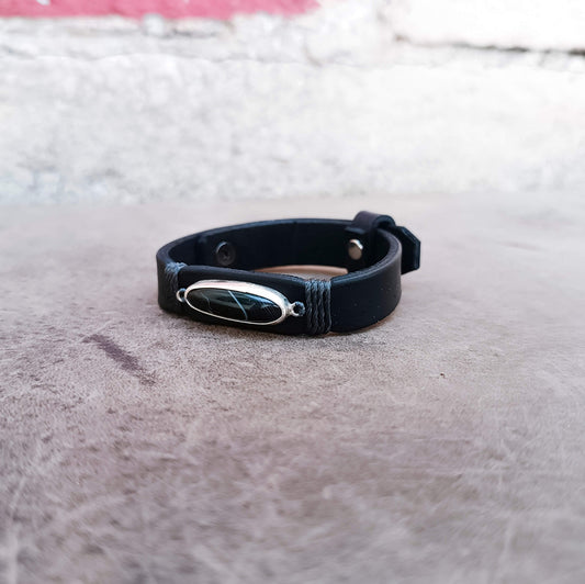 The Eclipse is a one-of-a-kind black obsidian leather bracelet with a handcrafted sterling silver pendant, premium black vachetta leather and unique natural vein.