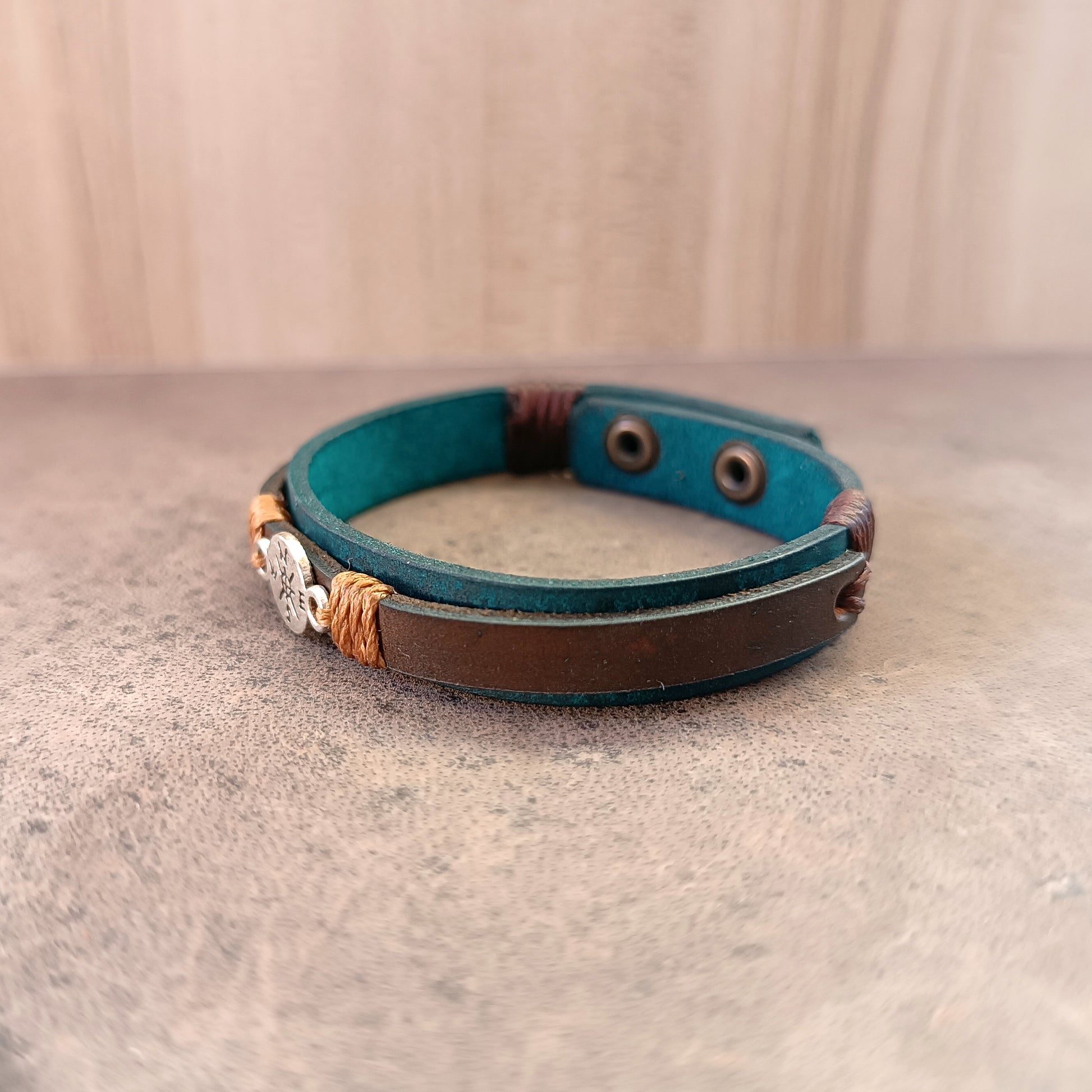Other Side view of Inner Compass Leather Bracelet, showing layers of petrol blue and dark brown leather, and the silver compass charm.