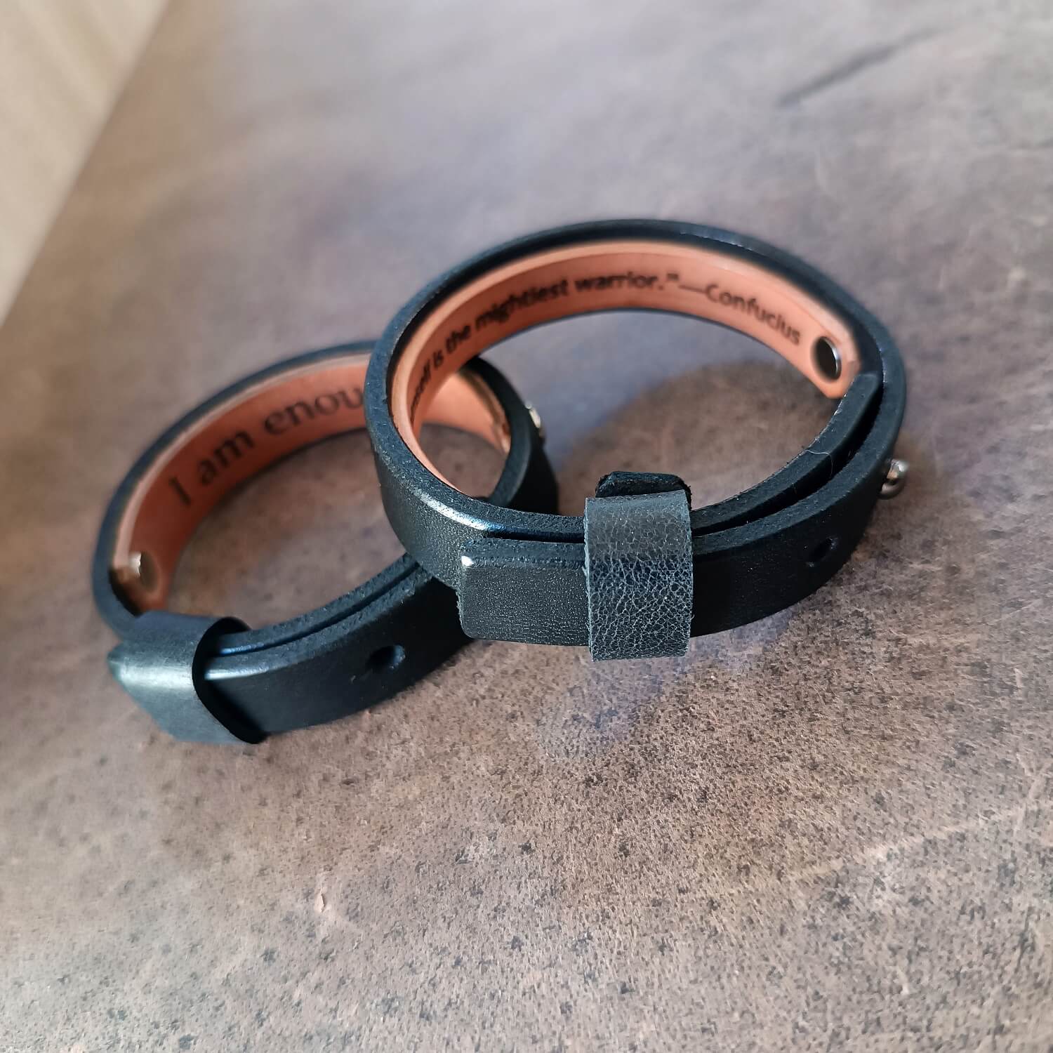 Personalized Black Vachetta Leather Bracelets with custom engraved hidden messages, one short with large fonts and one long with smaller, yet crispy clear fonts.