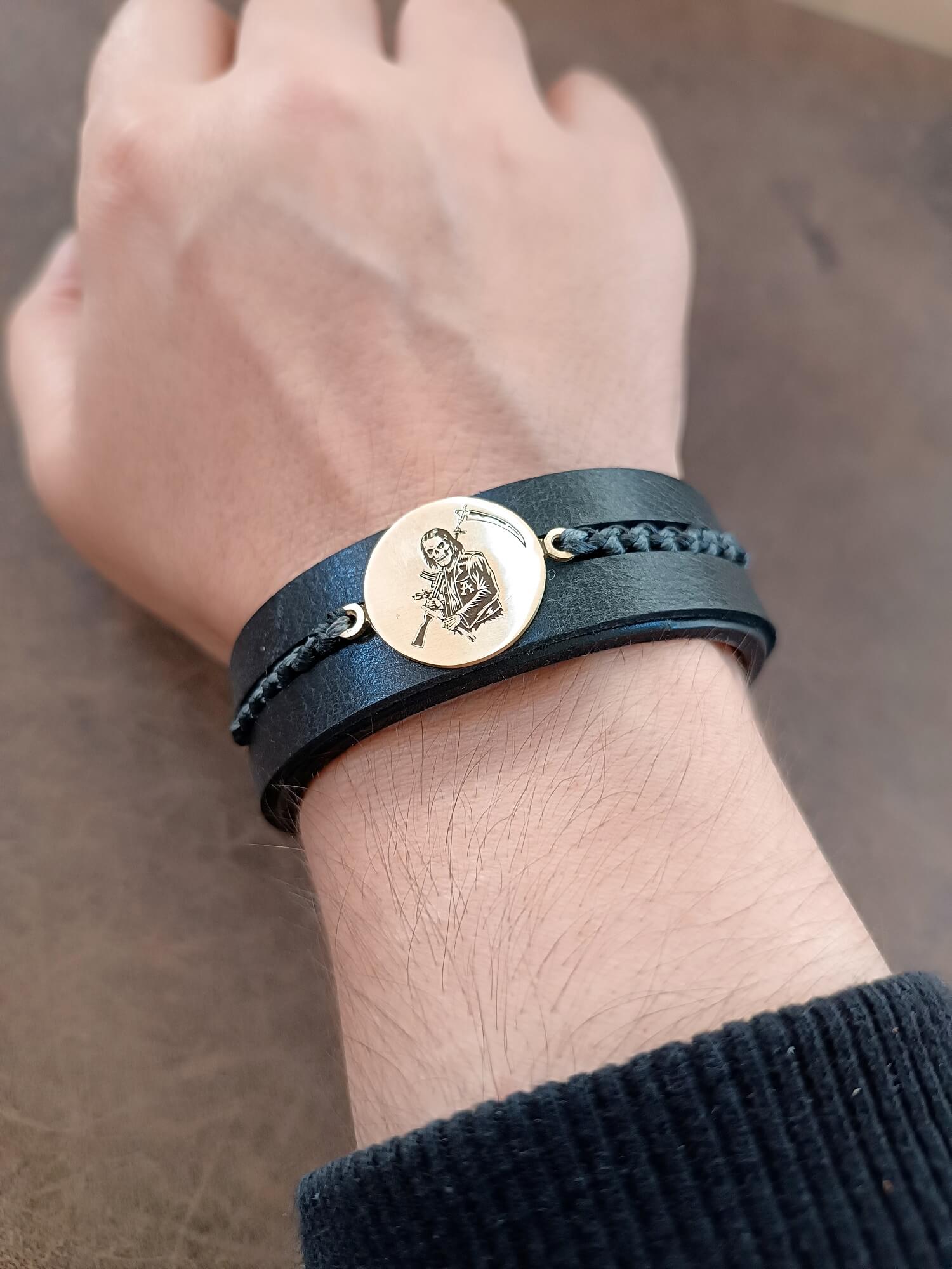 SAMCRO Black leather bracelet with a gold Reaper pendant worn on wrist