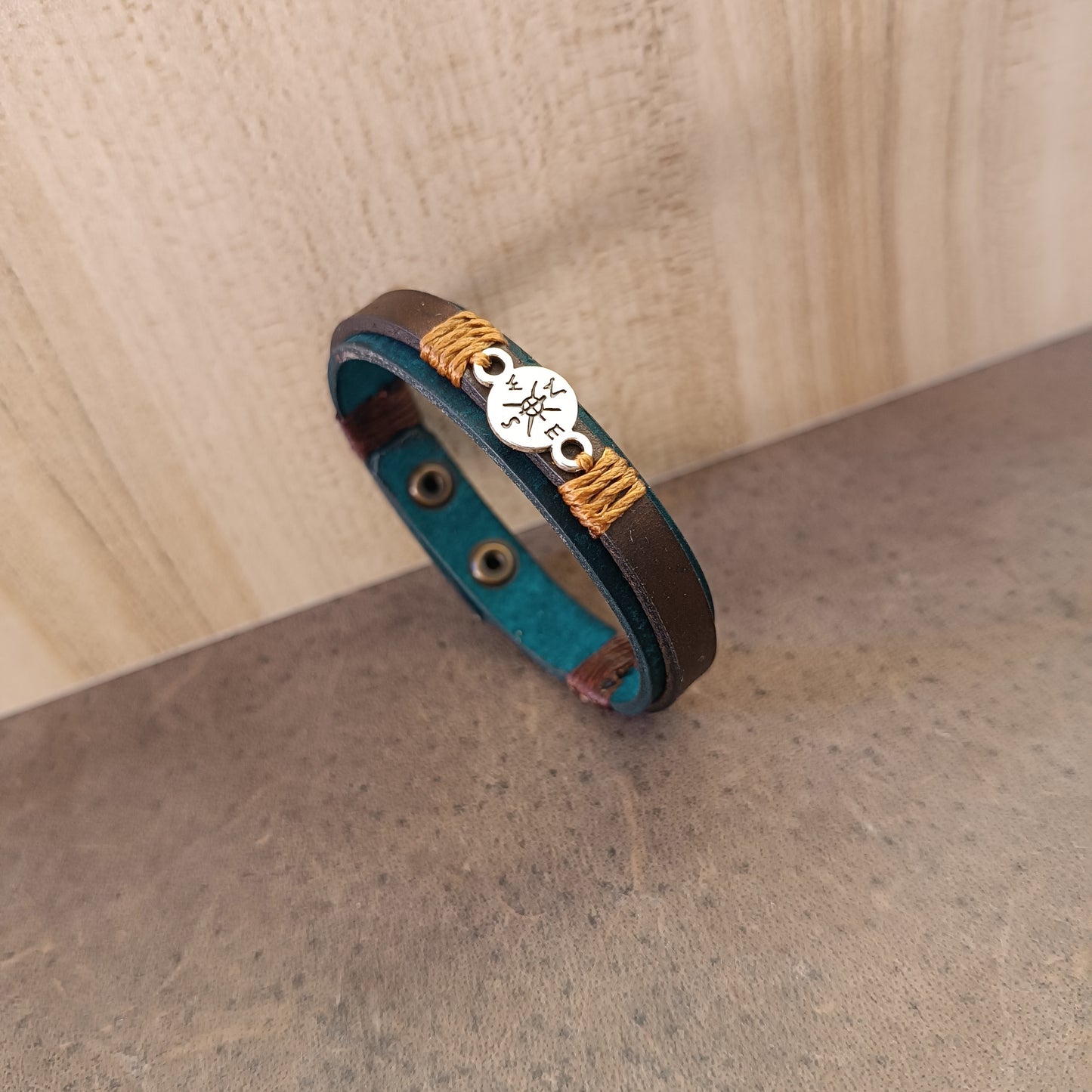 Side view of Inner Compass Leather Bracelet, showing layers of petrol blue and dark brown leather, and the silver compass charm.