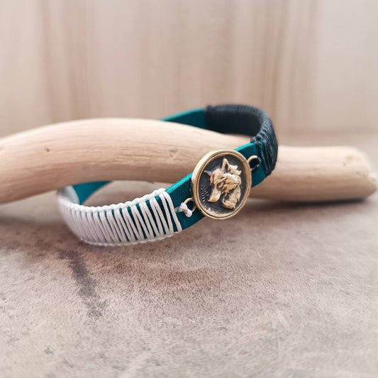 Side view of The Instinctive Shield Wolf Bracelet, showing the thickness of the blue Crazy Horse leather band and the intricate white and black macrame knotting.