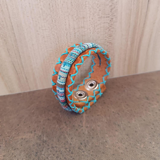 close up Side view showing layered Crazy Horse leather cuff with colorful cotton tribal cord and hand-stitched blue thread