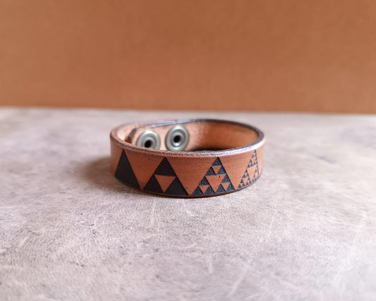 Brown leather bracelet with geometric pattern on a textured surface