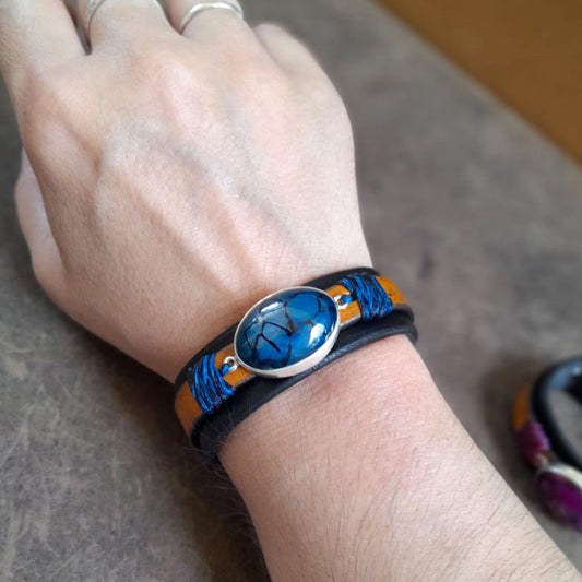 The Dragon Whisperer Bracelet worn on a woman's wrist, highlighting its layered leather, the captivating Blue Dragon Veins Agate, and its rugged yet refined style.