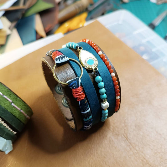 close-up after making: the red crystal, white howlite, and natural turquoise beads, and the brass enamel evil eye charm on The Warrior Stack leather cuff, highlighting their colors and textures.