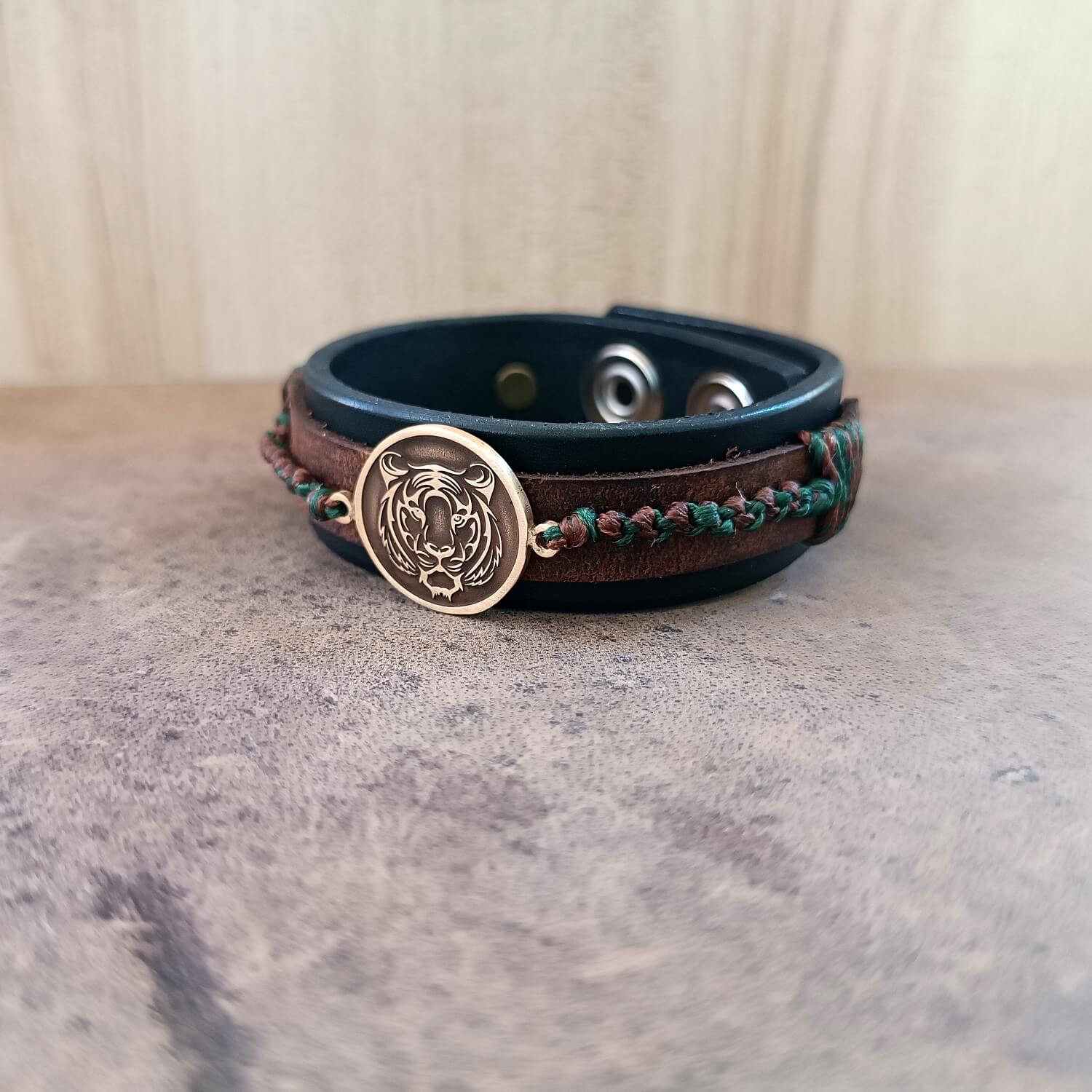 Leather bracelet with a tiger emblem on a textured surface