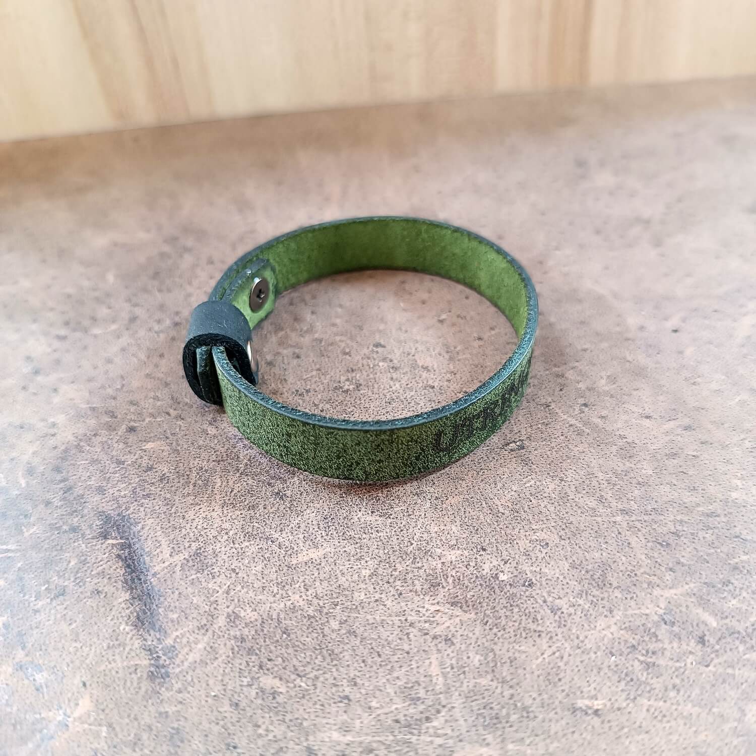 Green leather bracelet on a textured surface