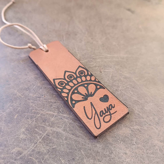 Leather bookmark with mandala design and 'Yaya' text on a textured surface
