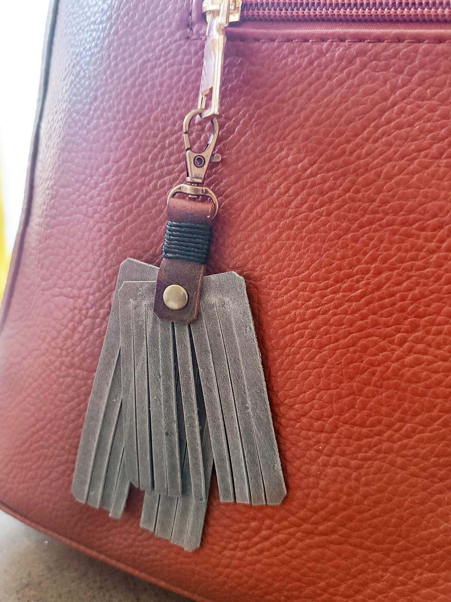 Tassel keychain attached to a brown leather bag