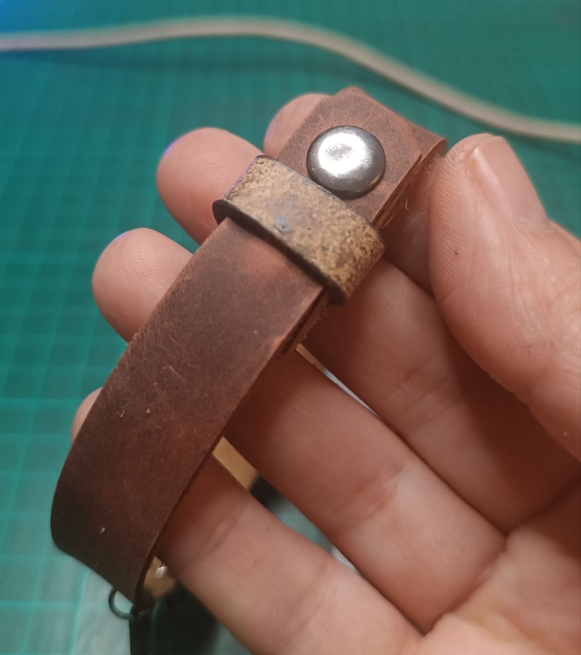 Back side of the brown leather anklet with a securing leather loop overlapping closure, for extra safety.