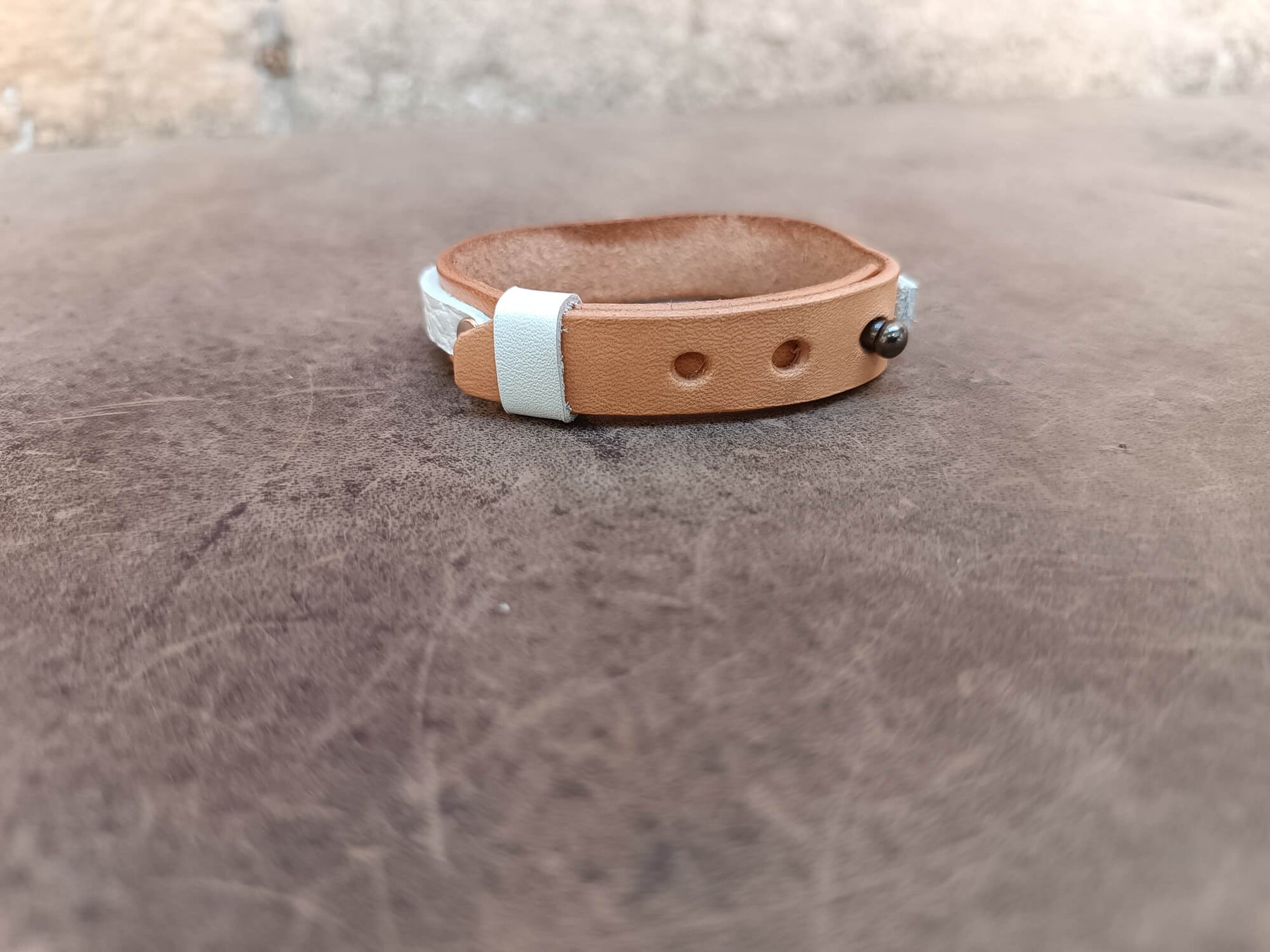 A handcrafted one-of-a-kind women's leather bracelet featuring a hand-cut natural moonstone set in sterling silver on raw untreated vachetta leather, backside view.