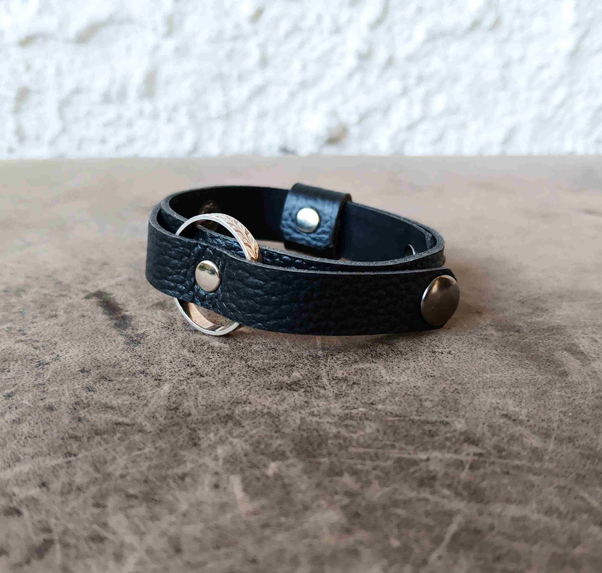 A black textured ringholder leather bracelet with silver-tone metal hardware.