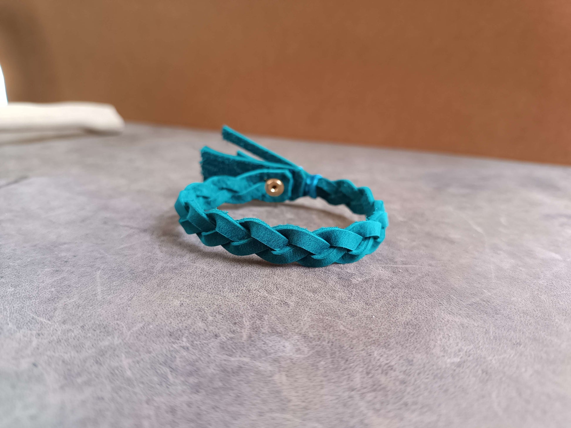Blue teal braided bracelet on a gray surface 