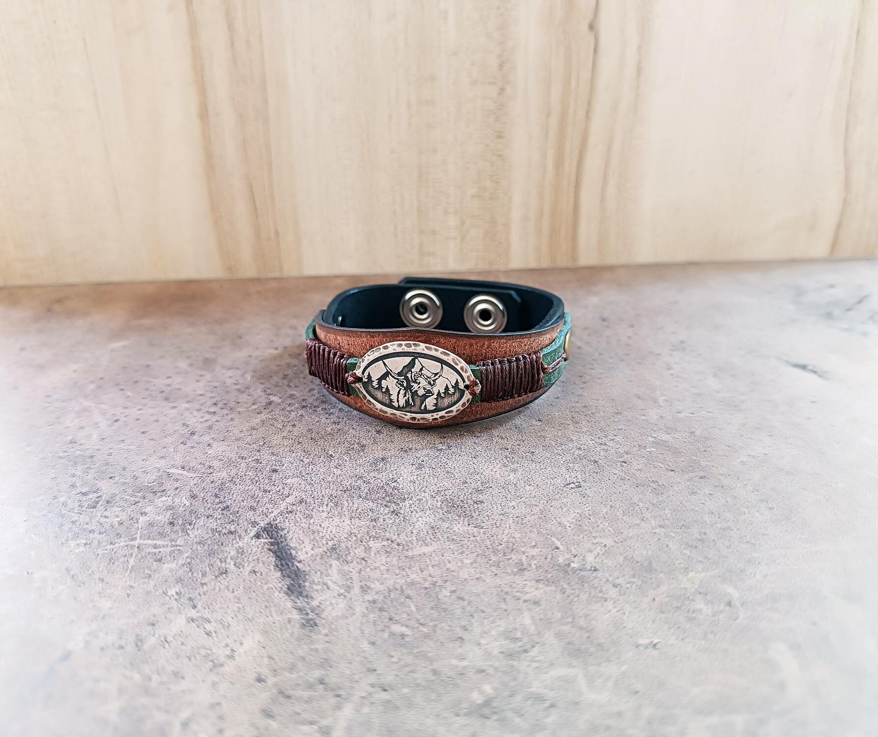 Front view of the three-layered leather cuff, highlighting the unique hexagon/tiara shape of the earthy brown layer and the macrame cord attachment.