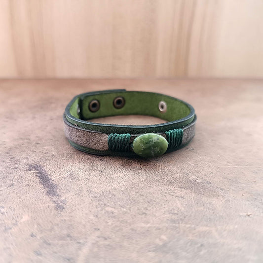 Green leather bracelet with a stone bead on a textured surface
