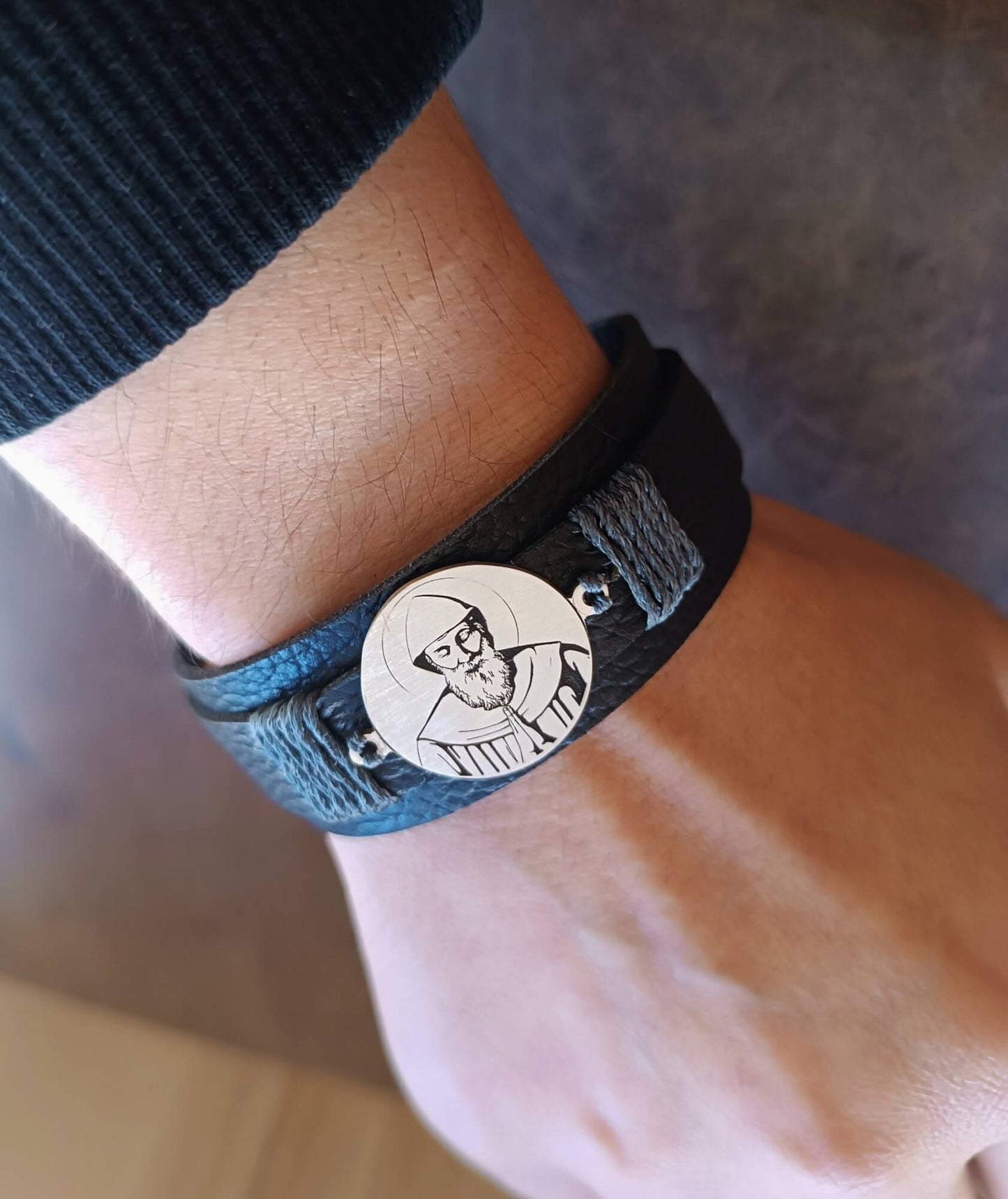 Bracelet with a circular emblem featuring a St. Charble pendant on a wrist.