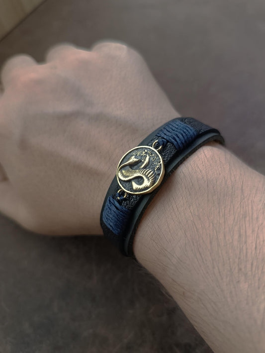 The Vincenzo Bracelet Cobra Edition worn on a wrist, showcasing the balance of elegance and grit. The black leather bands and dark blue cords contrast with skin, evoking the silent fury and controlled fire of a man who moves through shadows with purpose.