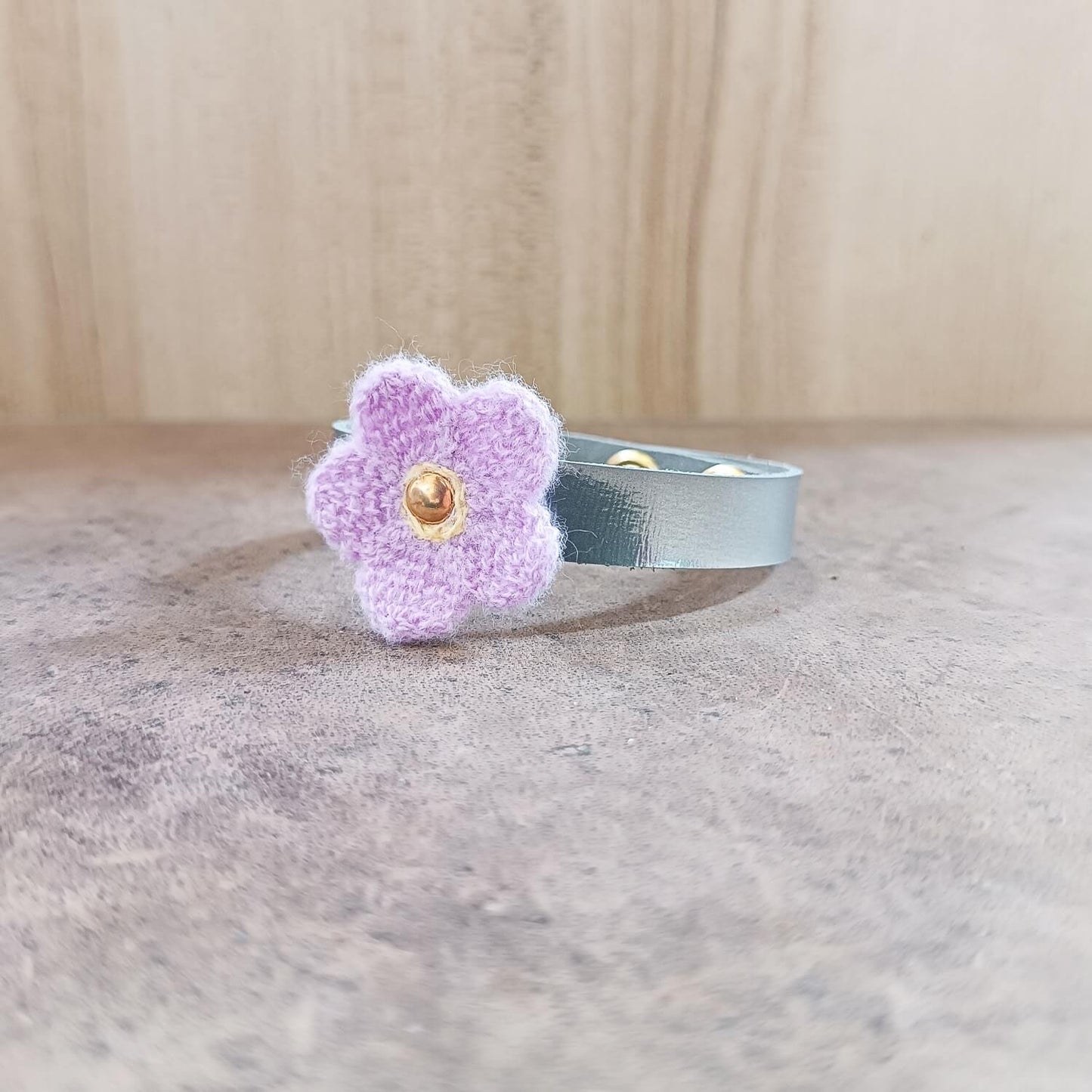 Silver bracelet with a purple flower charm on a wooden surface