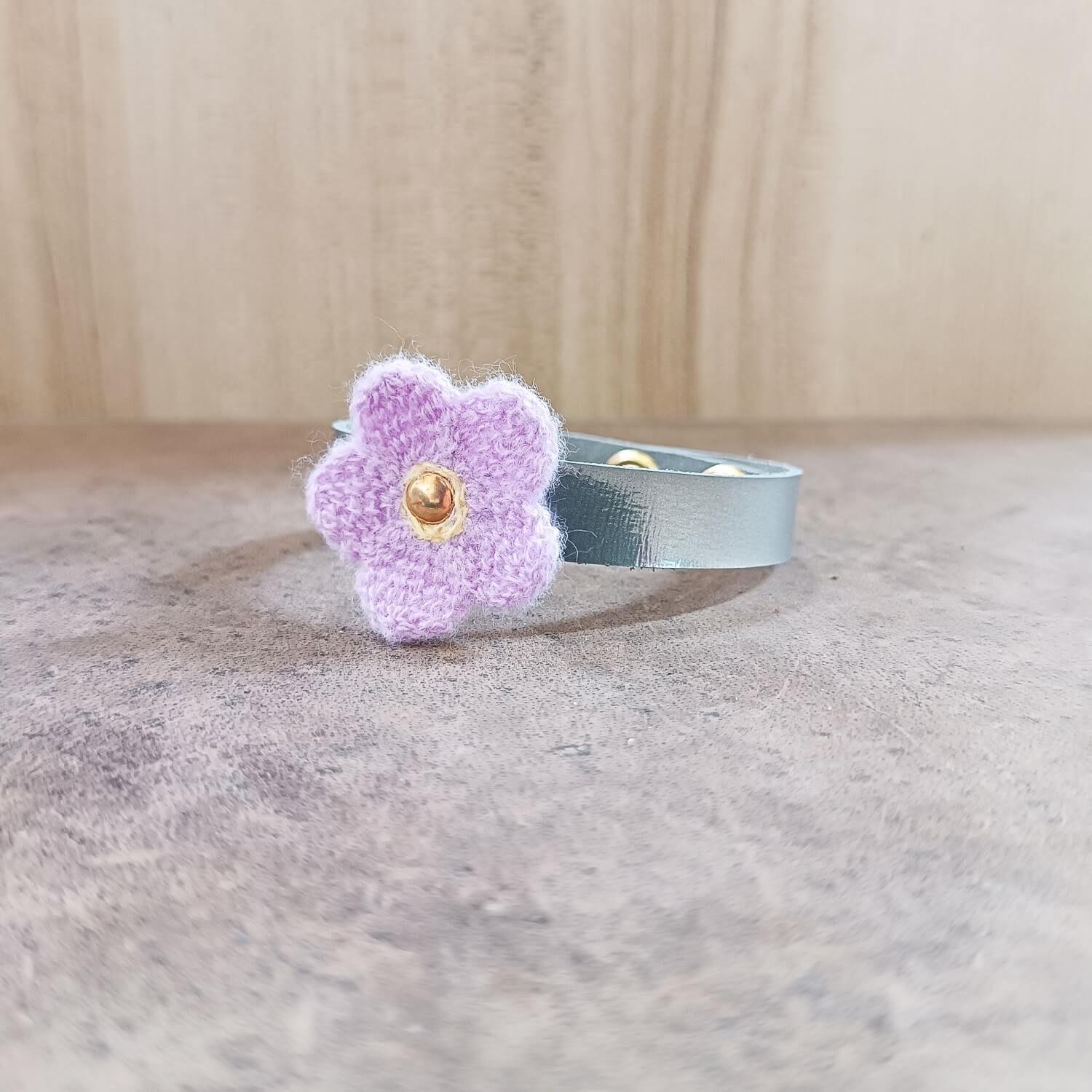 Silver bracelet with a purple flower charm on a wooden surface