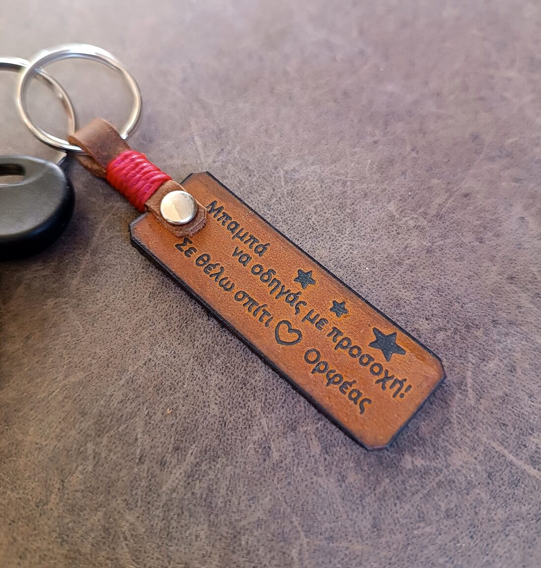 Brown leather keychain with engraved text on a gray surface