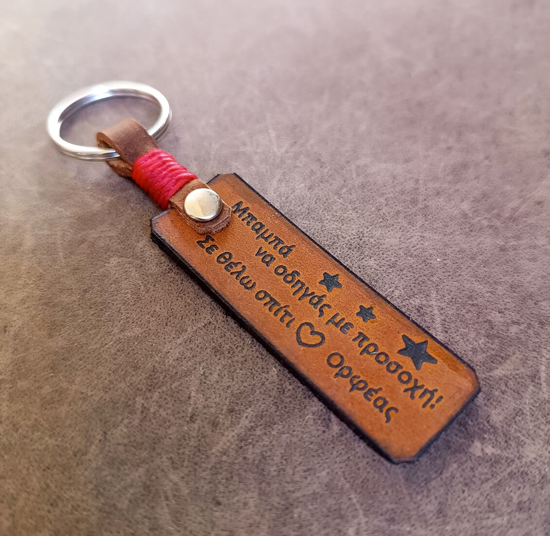 Brown leather keychain with engraved text on a gray surface