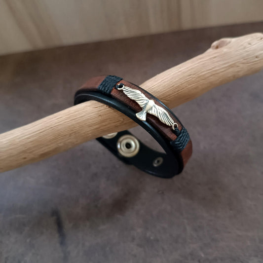 Bracelet with eagle charm on a wooden stick against a neutral background