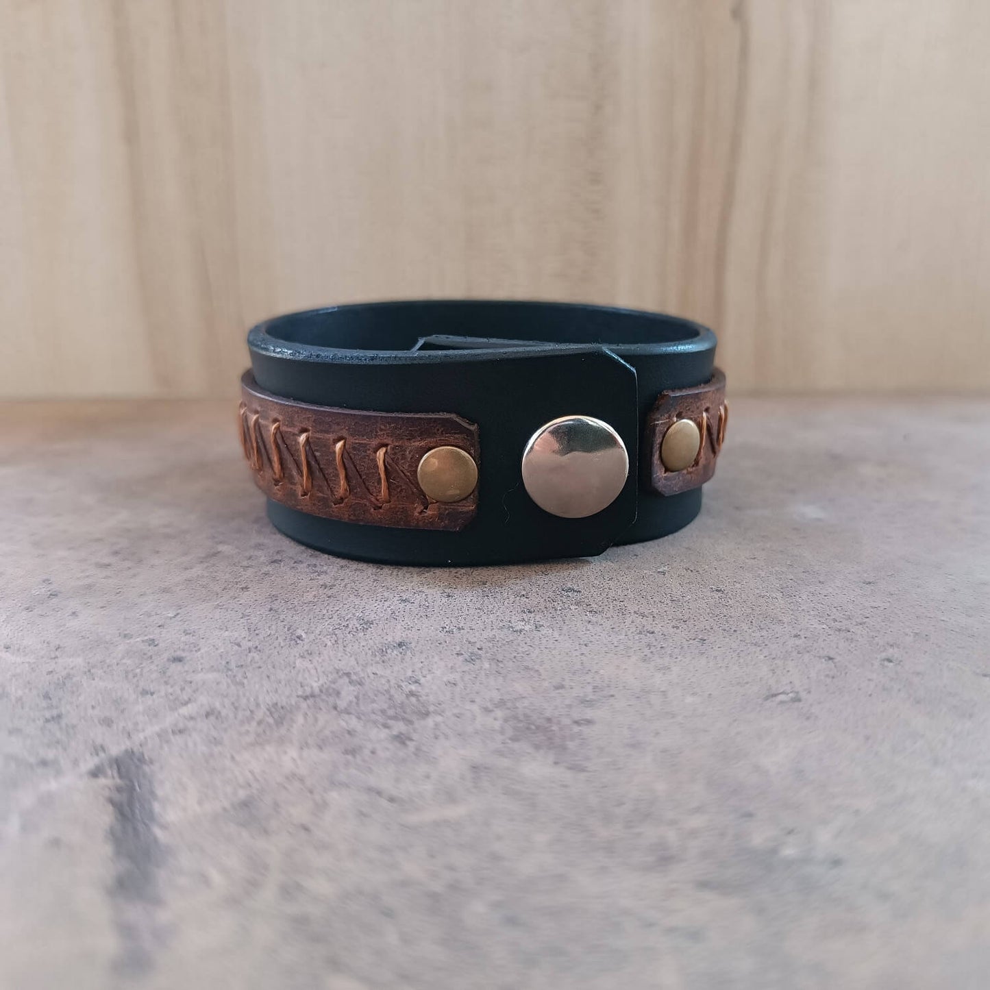 Back view of black leather cuff bracelet, highlighting premium oiled vachetta leather texture and stainless steel snap buttons.