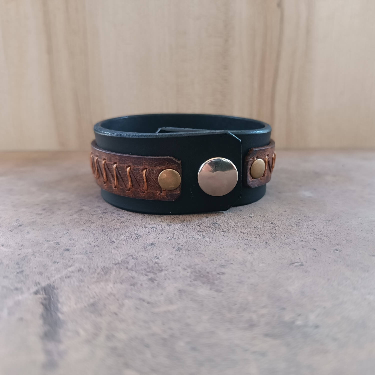 Back view of black leather cuff bracelet, highlighting premium oiled vachetta leather texture and stainless steel snap buttons.