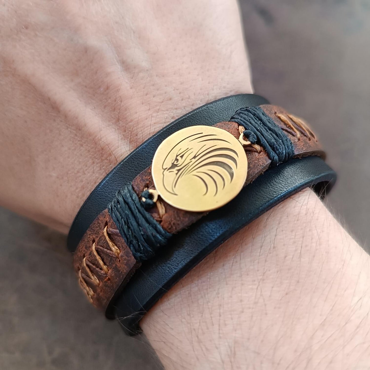 Men's wide black leather cuff bracelet with tribal eagle pendant worn on wrist, showcasing its masculine fit and statement look.