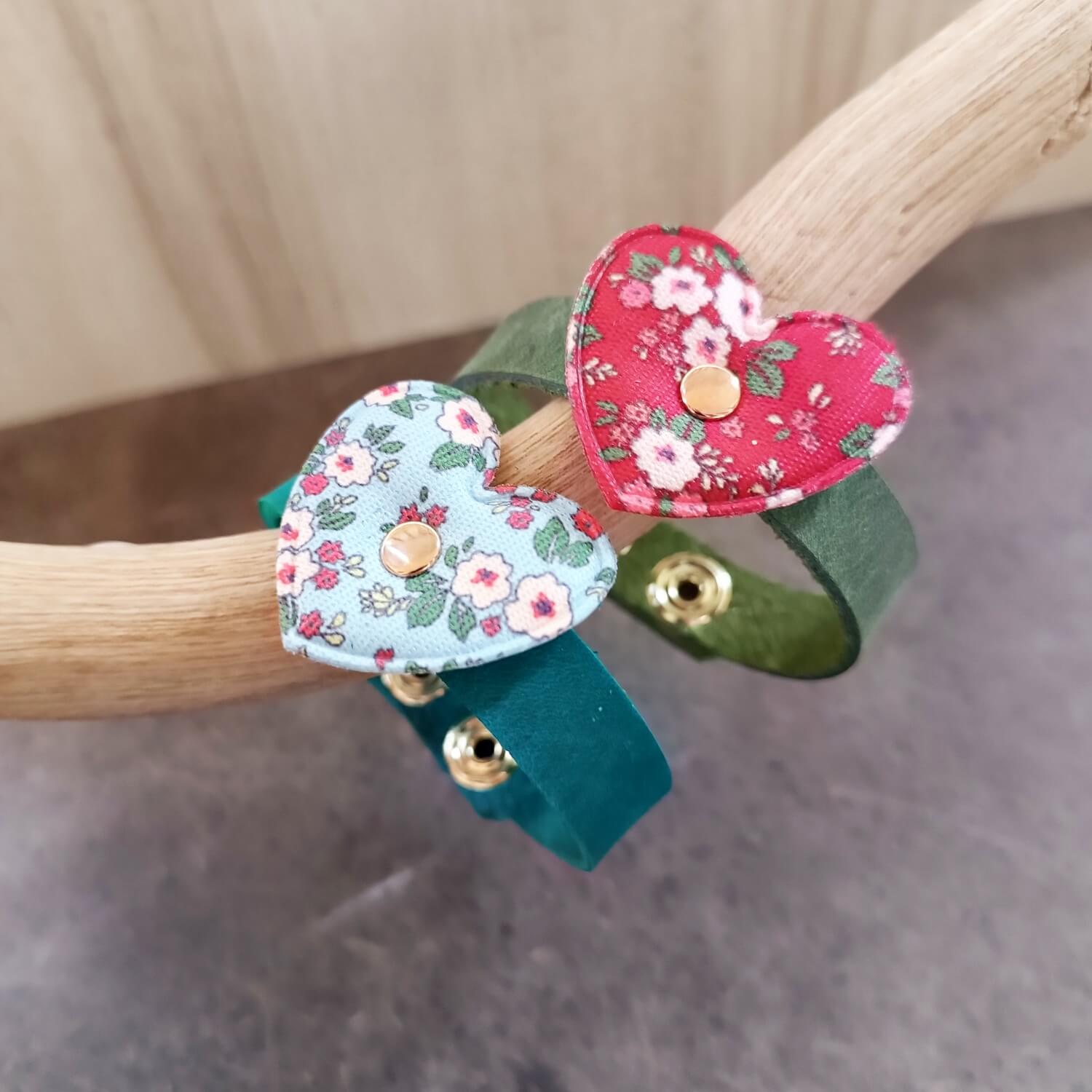 Two handmade leather bracelets for girls, one green with red floral fabric heart and one petrol blue with light blue floral heart close up