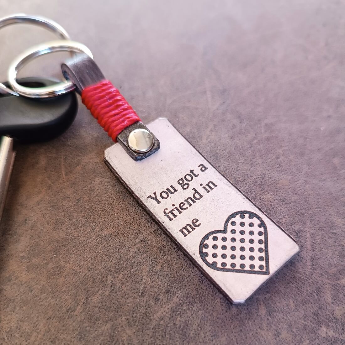 Keychain with engraved message 'You got a friend in me' on a textured surface