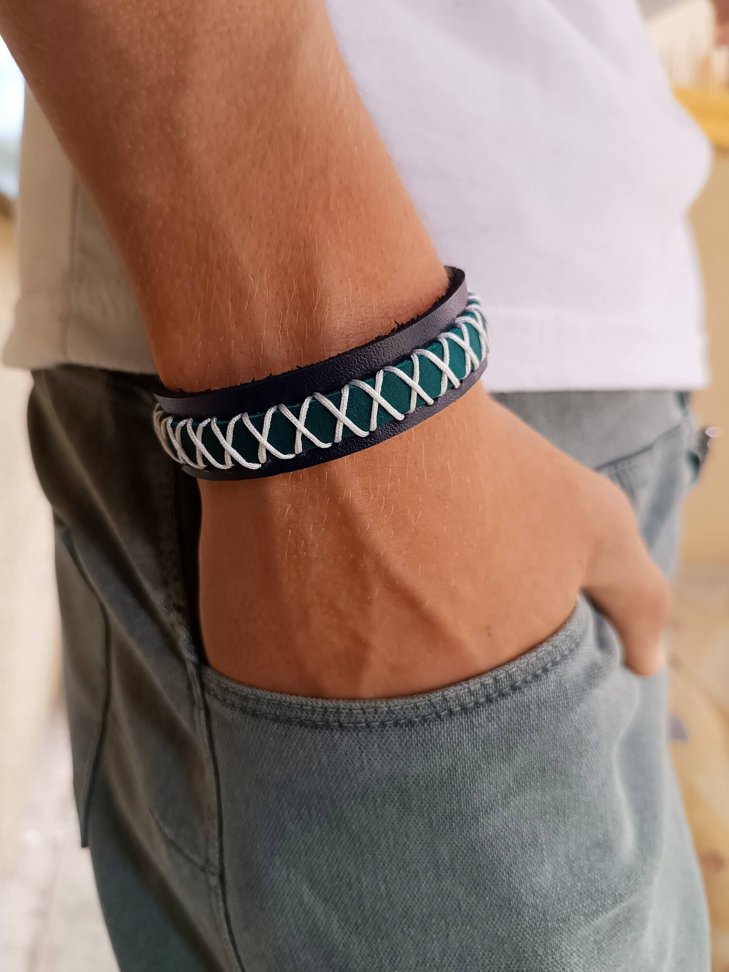 Close-up of a person wearing a navy blue and muted petrol braided bracelet on their wrist.