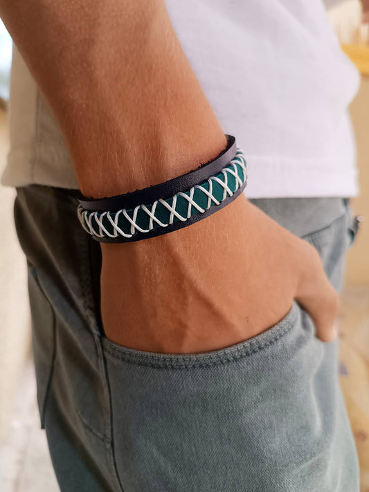 Close-up of a person wearing a navy blue and muted petrol braided bracelet on their wrist.