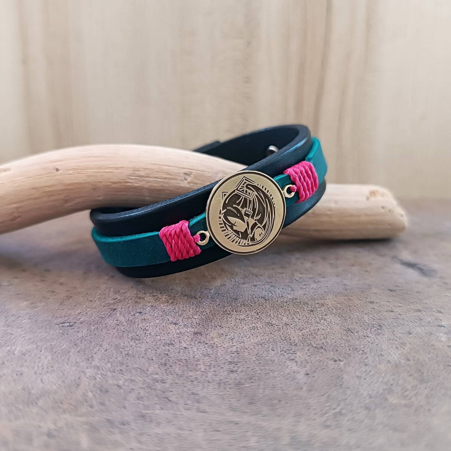 Bracelet with blue strap, pink accents, and gold Hatsune Miku pendant on a neutral background