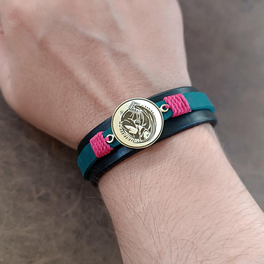 Bracelet with blue strap, pink accents, and gold Hatsune Miku pendant worn on wrist