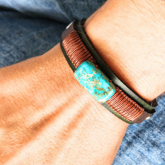 close up shot of a wrist wearing a muted olive green leather cuff bracelet, featuring dark brown cord braiding and natural imperial jasper stone.