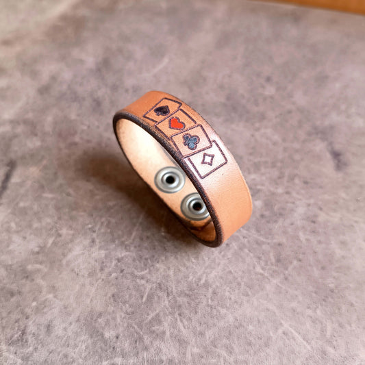 Leather bracelet with card suit symbols on a textured surface