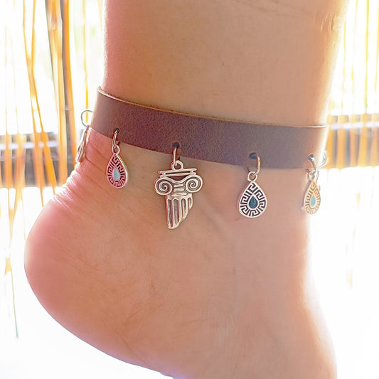 Ankle bracelet with charms on a person's ankle against a blurred background